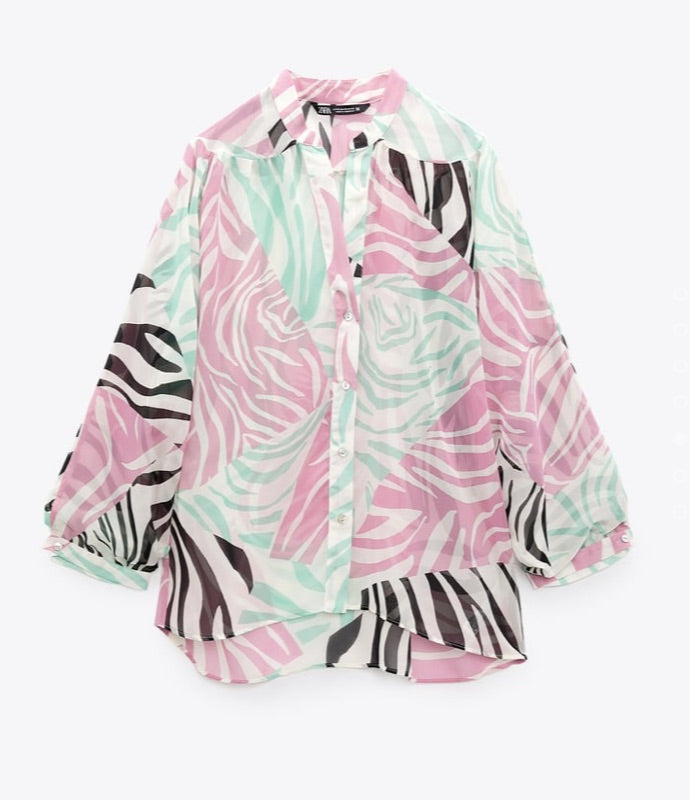 A semi-sheer blouse with a round collar and V-neckline, featuring a zebra and floral print in pink, green, and black colors.