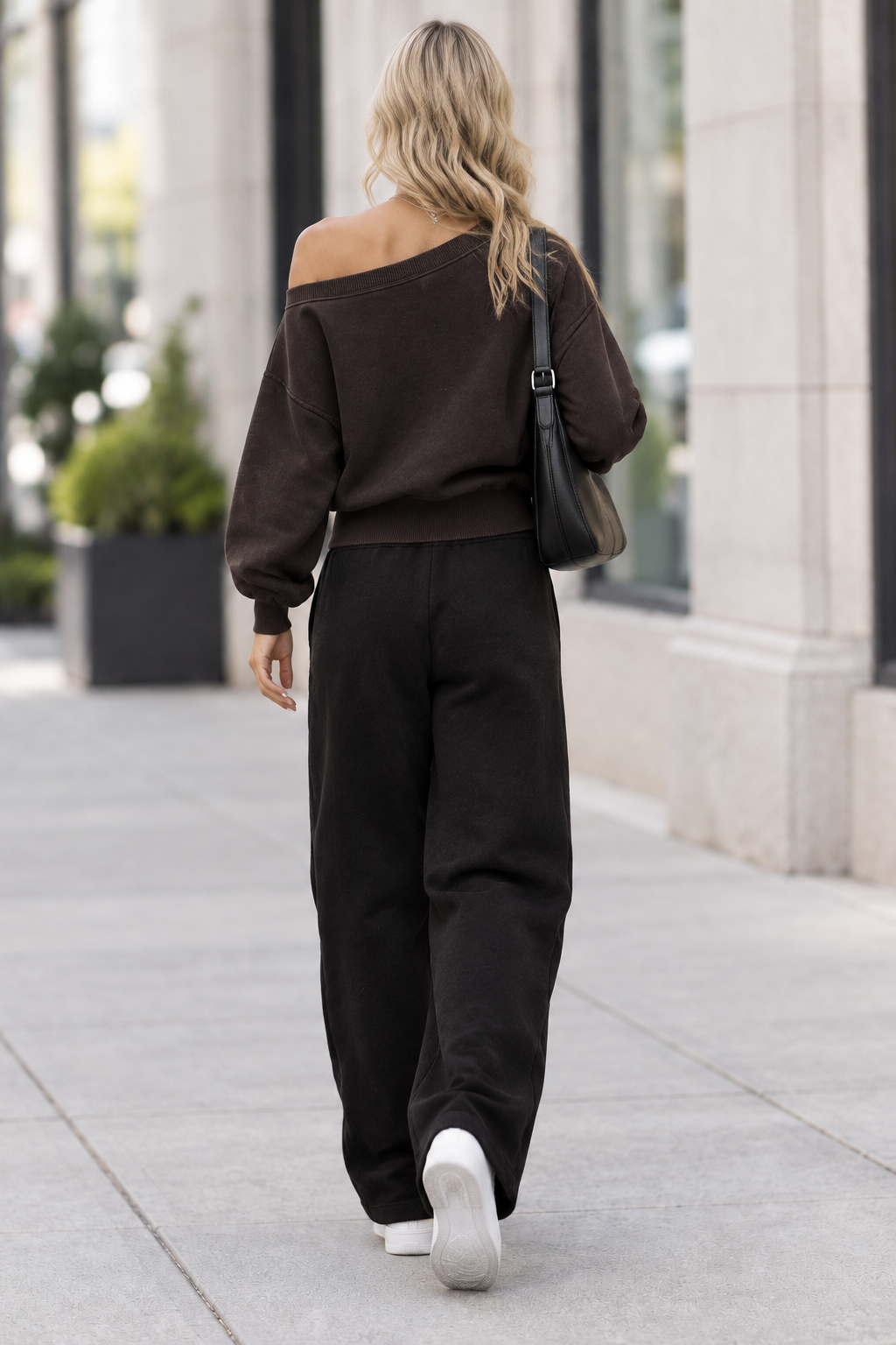 Back view of blonde model wearing sweatshirt on city sidewalk