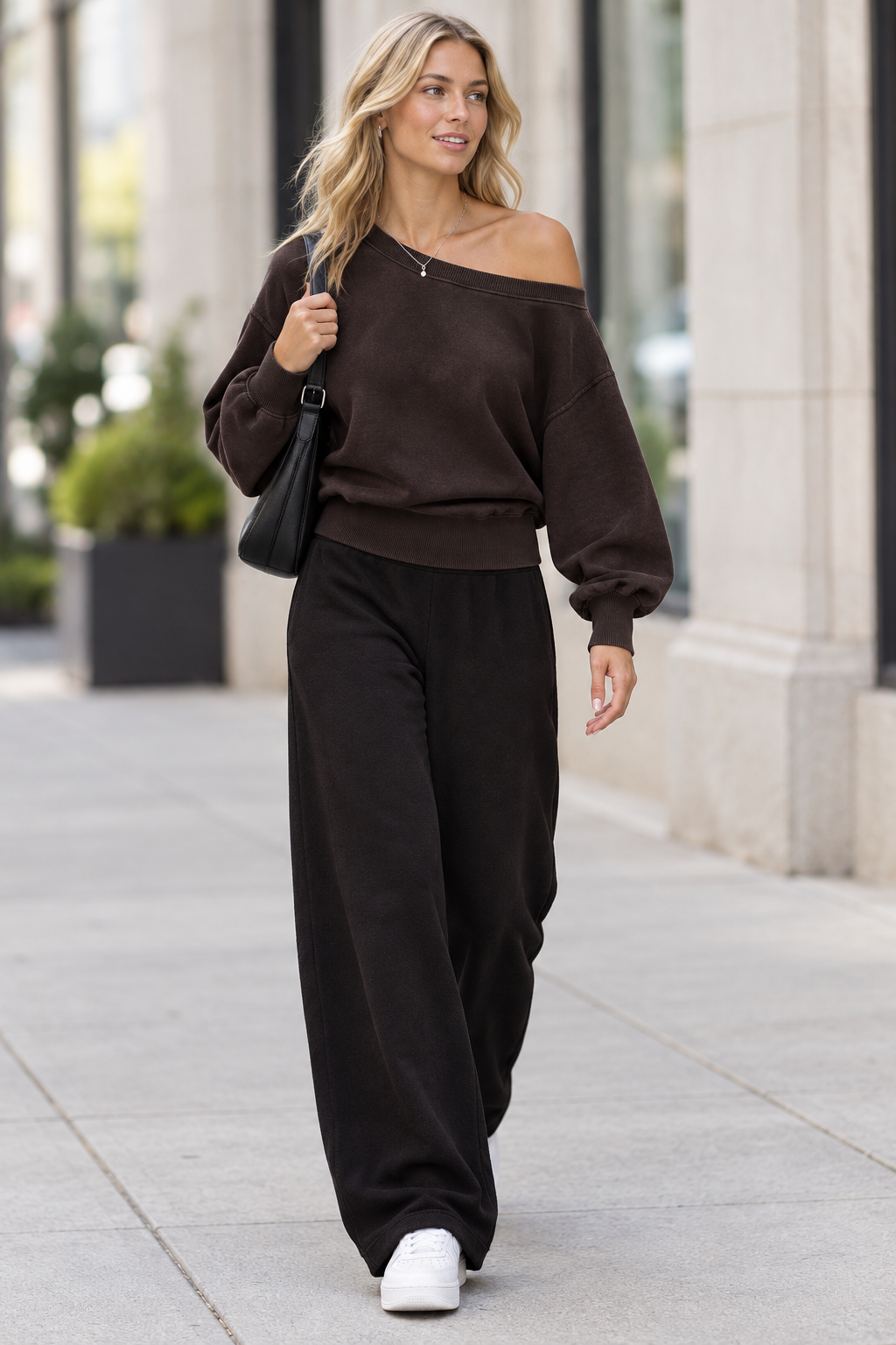 Blonde model wearing the reference sweatshirt walking on a city sidewalk